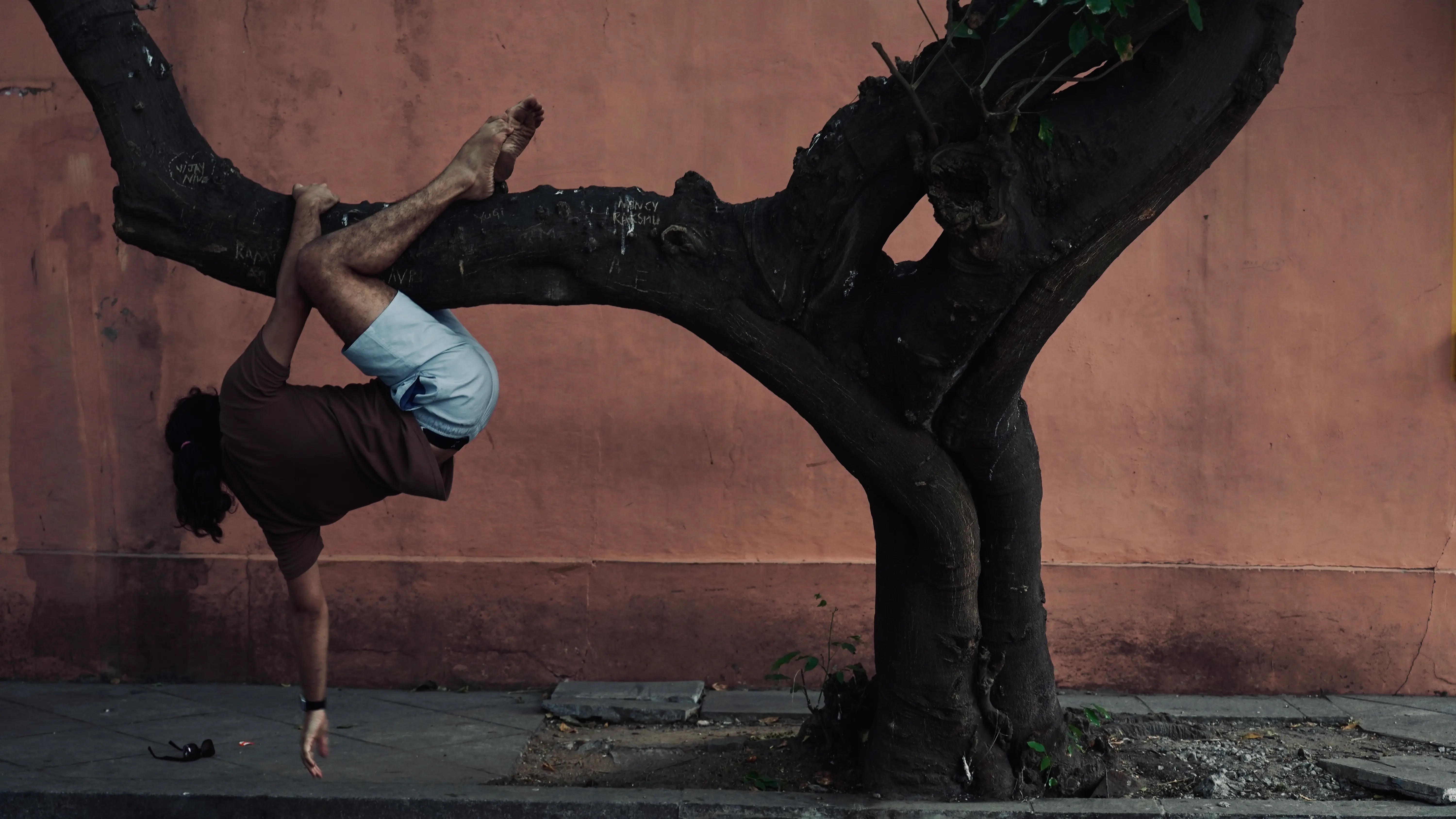 Lokesh suspended upside down from a tree while improvising outdoors.