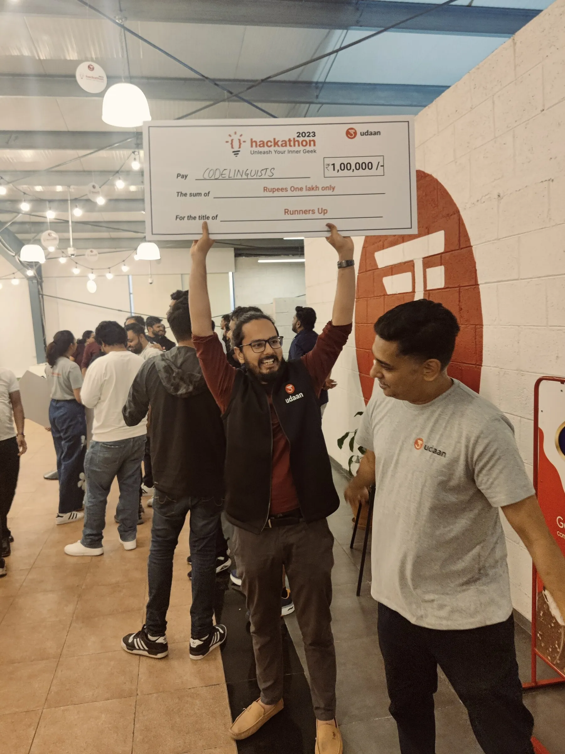 Lokesh celebrating a hackathon runners-up award while holding an oversized cheque.