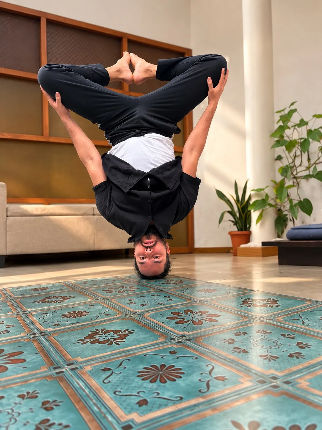 Lokesh balancing upside down in a compact headstand at home.