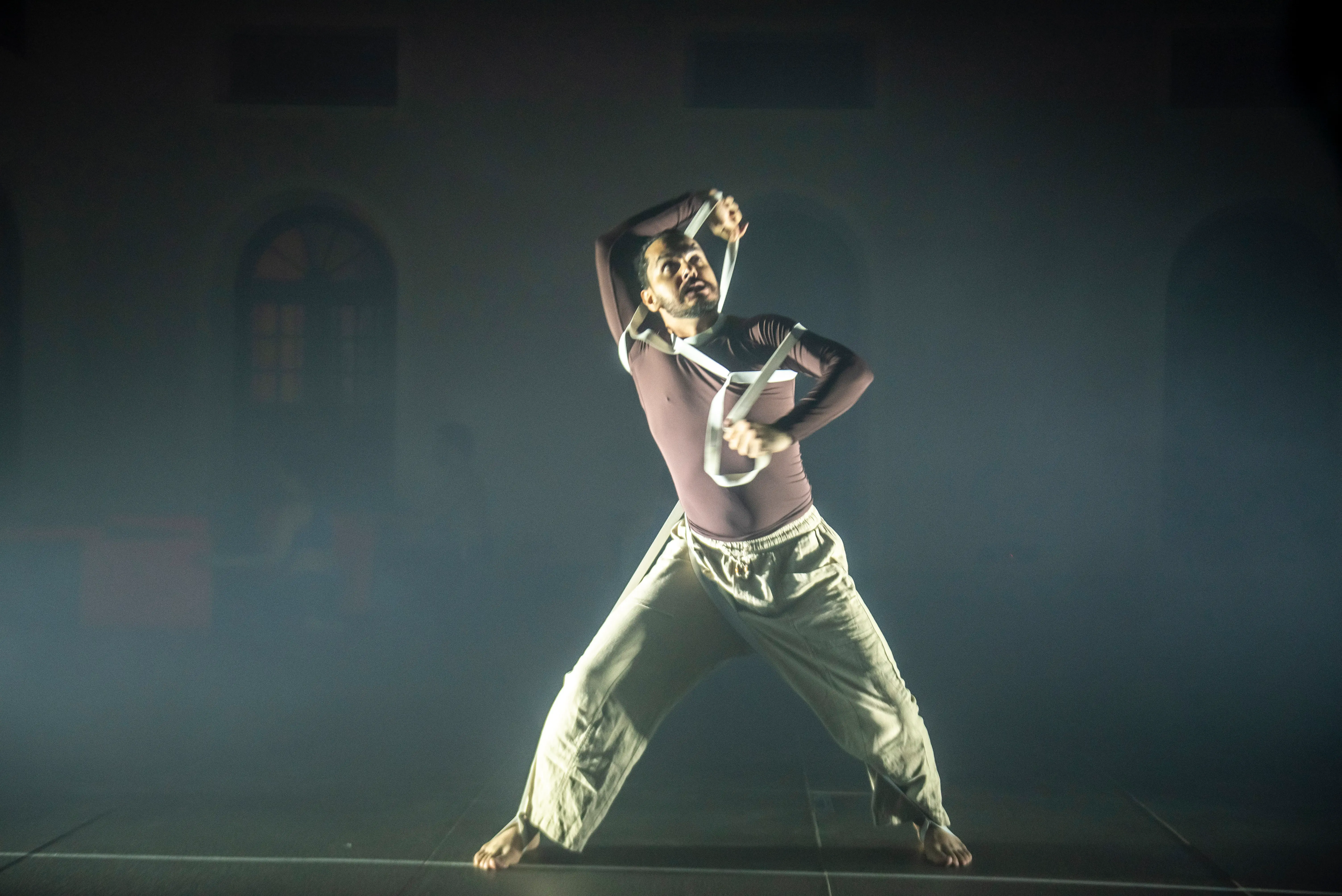 Lokesh performing Lost Diaries with white straps on a dark, atmospheric stage.