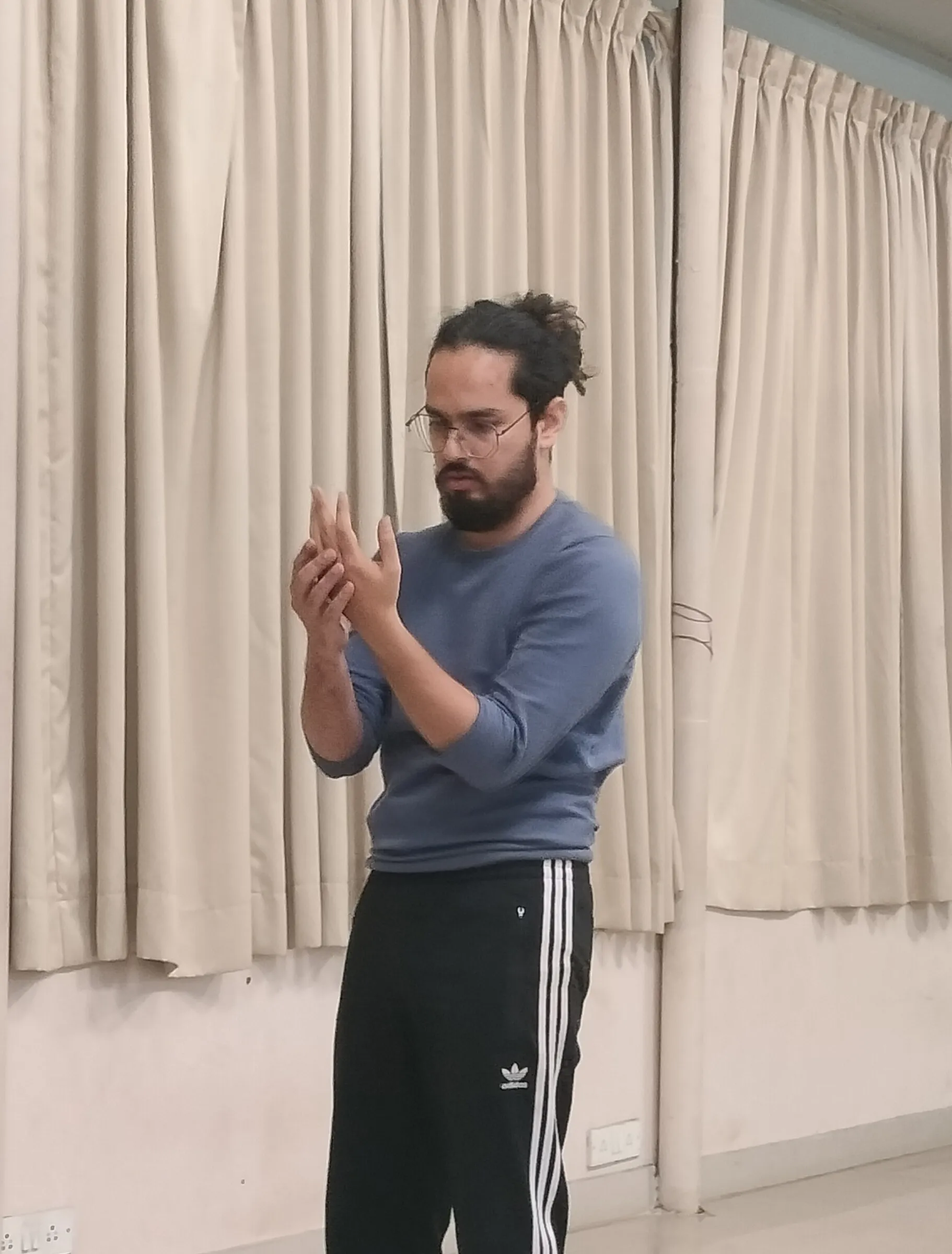 Lokesh studying a hand gesture during movement practice in a studio.
