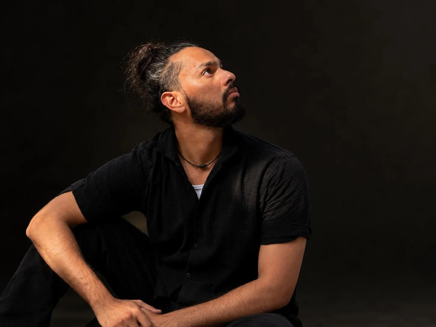 Lokesh seated in a studio portrait, looking toward a shaft of light.